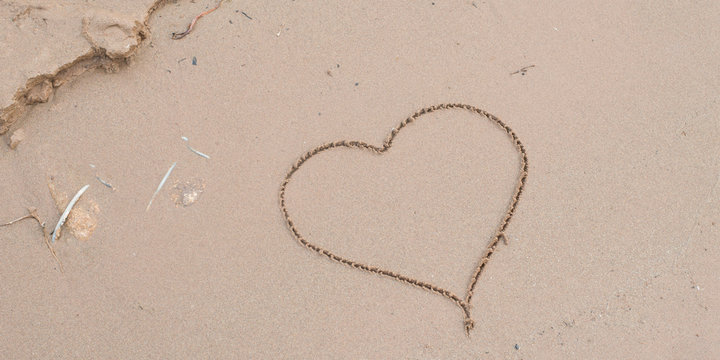 Heart drawn in the sand. Beach background. vertical photo
