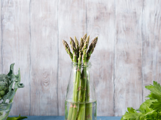 Organic asparagus in a glass bottle on wooden textured background. copy space