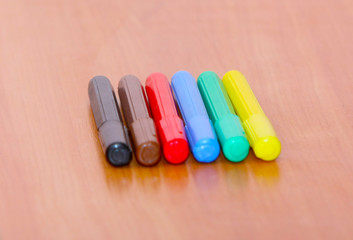 Many multi-colored felt-tip pens on a wooden table. Colored markers on wooden background. Free empty space.