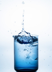 ice dropped into blue glas with white background