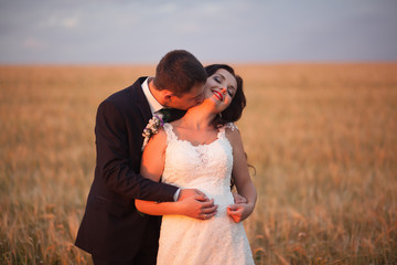 Beautiful romantic wedding couple of newlyweds hugging in park on sunset