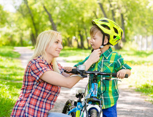 Fototapeta na wymiar mother taking care of her son, wearing his bicycle helmet