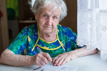 Elderly woman fills in receipts for utilities.