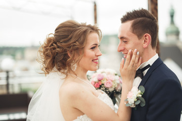 Beautiful couple, bride and groom posing on balcony with backgrounf of old city