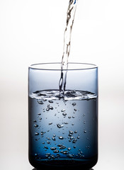 water pour to blue glass on white background