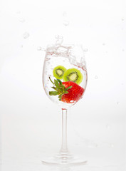 Fototapeta na wymiar splashing strawberry and kiwi into water glass on white backgrou