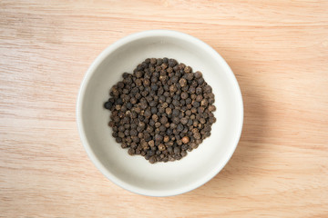 Fototapeta na wymiar bowl of black dried pepper on a wood background