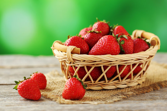 Fresh and tasty strawberries in basket on a grey wooden table