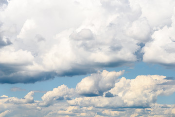 White Cumulus Clouds And Grey Storm Clouds Gathering On Blue Sky