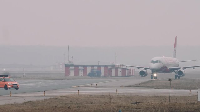 The Superjet 100 moving on a taxiway in the airport in a rainy day. Some airport facilities in the background, 2160p UHD 4k