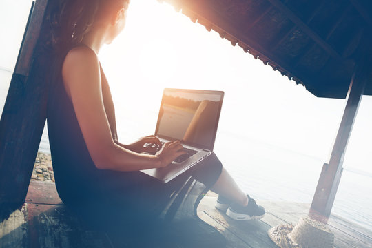 Woman Working With Laptop On The Beach In Shadow Shelter. Blurry Effect, Lens Flares Effect, Intentional Sun Glare