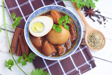 eggs and pork in brown sauce. three layer pork with eggs in sweet gravy sauce. braised pork belly and chicken eggs in soy sauce with five spice background. thai food.