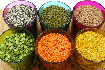 Multicolored clear glasses with various legumes ( green peas, re