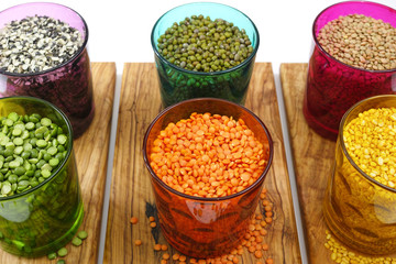 Multicolored clear glasses with various legumes ( green peas, re