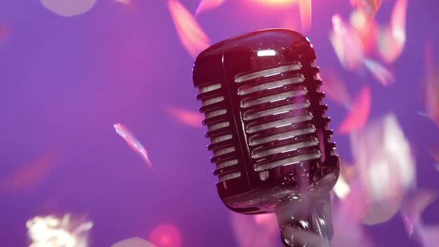 Retro microphone against blurry purple stage lighting with glitter confetti