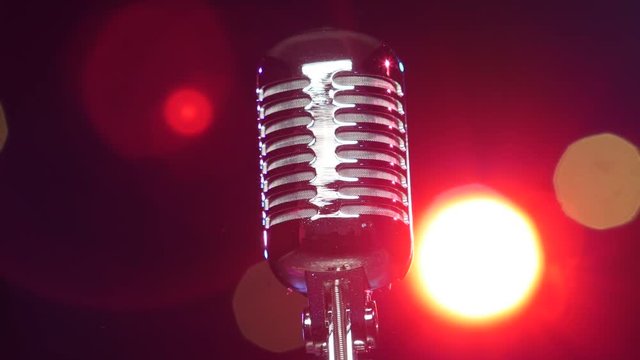 Retro shiny microphone rotating against blurry flashing lights. Close-up