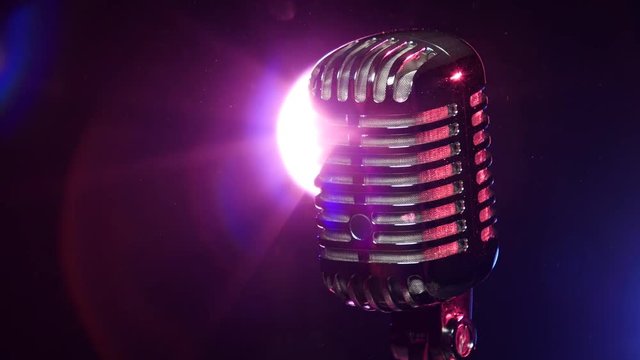 Classic microphone rotating on background lamp stroboscope in dark