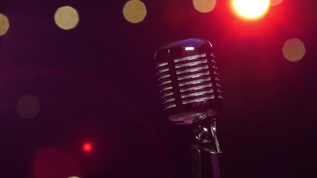 Classic microphone against dark blurry background with bright flashing lights