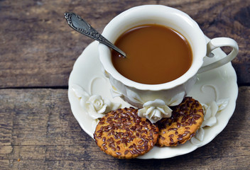 Сoffee with milk in vintage porcelain cup with vegan cookies on old wooden background close up. Selective focus