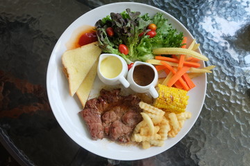 Grilled steak, French fries, bread and vegetables set
