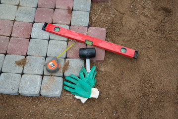 , stone blocks rubber hammer level gloves and tape measure