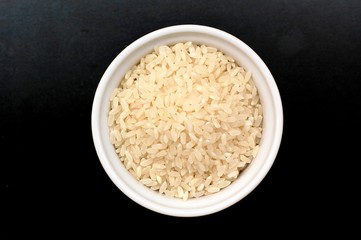 Risotto rice in the bowl on the black background