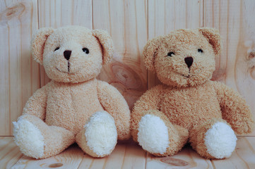 Two teddy bears sitting together on wooden background. Friendship concept. Greeting card on wood.