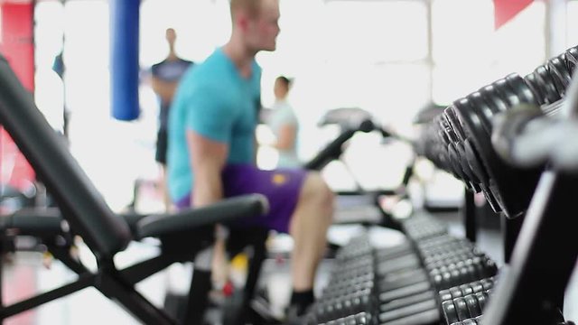 Defocused silhouette of young man doing dumbbell bench press exercise in gym - Powered by Adobe