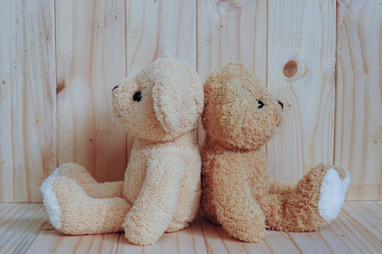 Two teddy bears sitting together on wooden background. Friendship concept. Greeting card on wood.
