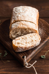Ciabatta with herbs on wooden background