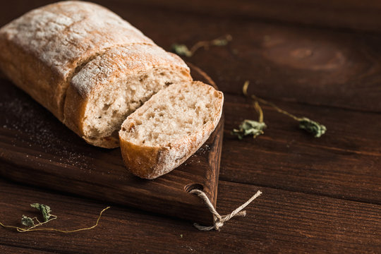 Ciabatta with herbs on wooden background