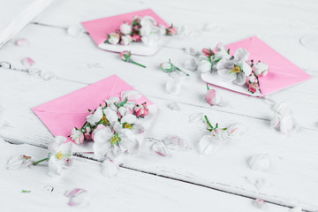 pink envelopes with flowers on white wooden background, closeup