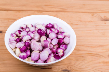 Bowl of peeled shallots onion and garlic on wooden table