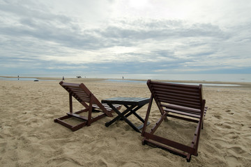 Fototapeta na wymiar Cloudy sky on the beach with table and chair