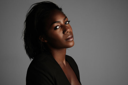 black woman in a dark roow with a soft light, showing shiny skin