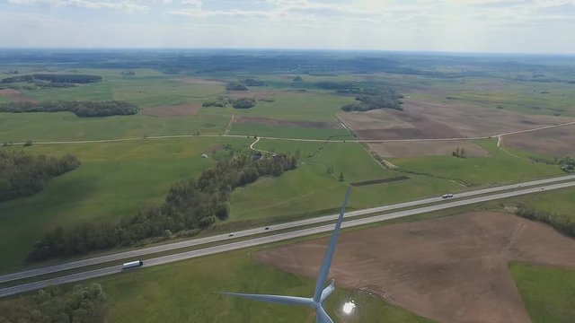 Aerial view: Single wind turbine with sky background road with traffic