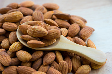 Almonds on wooden spoon wood background