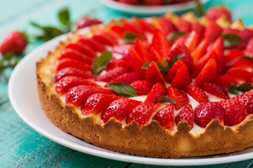 Tart with strawberries and whipped cream decorated with mint leaves.