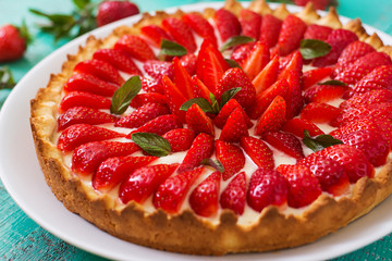 Tart with strawberries and whipped cream decorated with mint leaves.