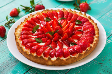 Tart with strawberries and whipped cream decorated with mint leaves.