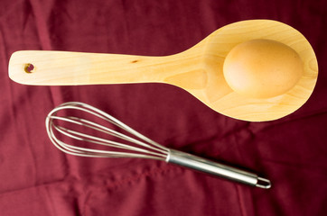 wooden spoon, metal whisk and egg for a minimalist composition