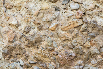 Ancient roughness stone wall. A lot of small stones. Beige texture. Can be used as background