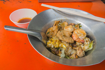 Fried noodle mix with shrimp, pork and egg, street food in Chinatown of Bangkok, Thailand