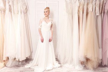 Fototapeta premium Cute young woman is trying on bridal gown