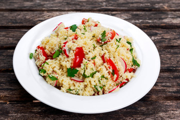 Homemade Fresh Couscous salad with vegetables, in white plate.