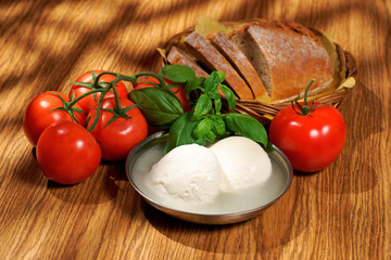 Mozzarella, tomatoes, basil, bread, composition on a wooden table