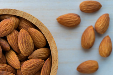 Almonds in brown bowl on wooden background