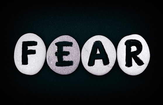 Word Fear spell out from stones with letters and black background. Letters drawn by me
