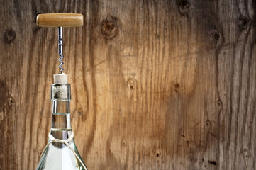 Corkscrew and wine bottle on wooden background
