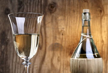 Glass and bottle of white wine in front of rustic wooden background
